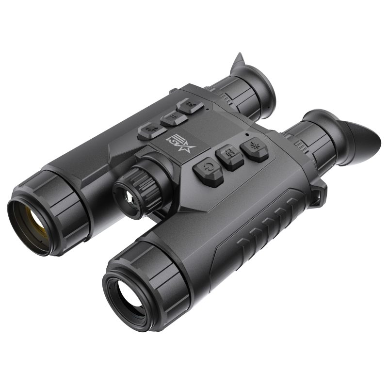 AGM Global Vision ReachIR LRF 25-384 thermal imaging monocular, black, held in hand, showing its lens and controls, against a blurred outdoor background.