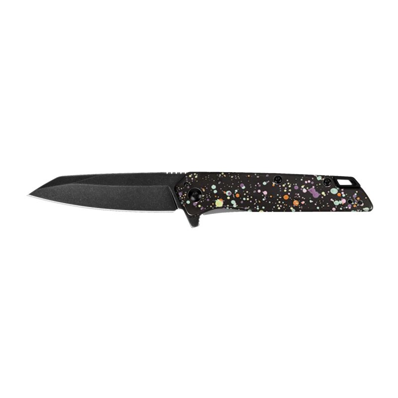Kershaw Misdirect folding knife with a black reverse tanto blade and a unique 80s splatter pattern handle, shown open on a rugged surface.