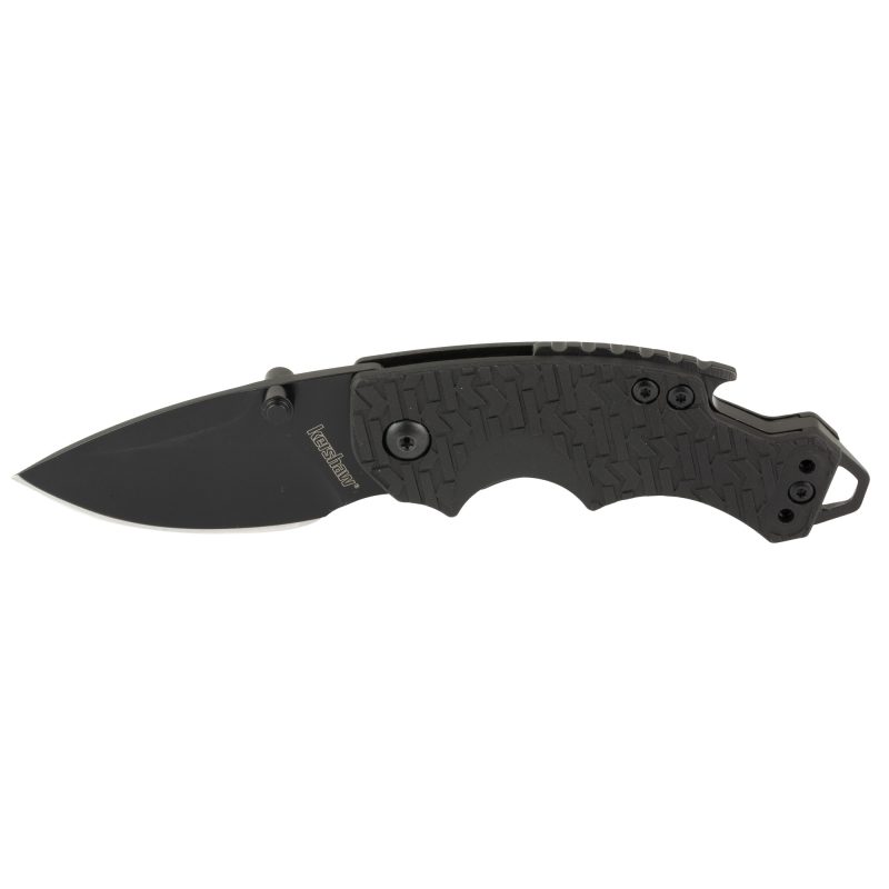 Kershaw Shuffle 2.4 inch black oxide folding knife with a black handle and black drop point blade, shown closed on a rustic surface.