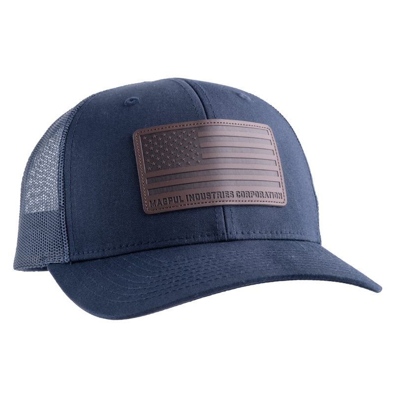 Navy blue Magpul Industries Standard Leather Patch Trucker Hat with a brown leather American Flag patch on the front, mesh back, and adjustable snapback closure.