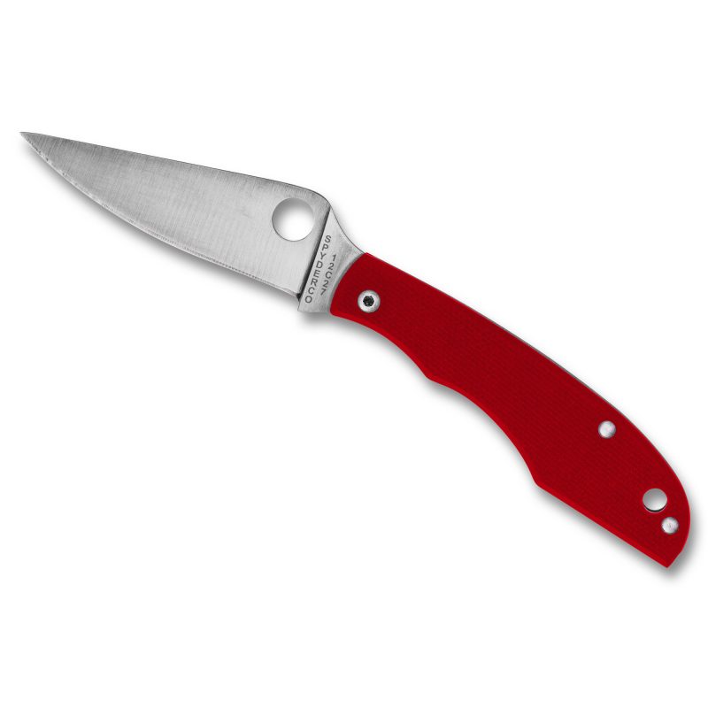 Red G-10 handle Spyderco Grasshopper folding knife with a satin silver drop point blade, open on a rustic surface.