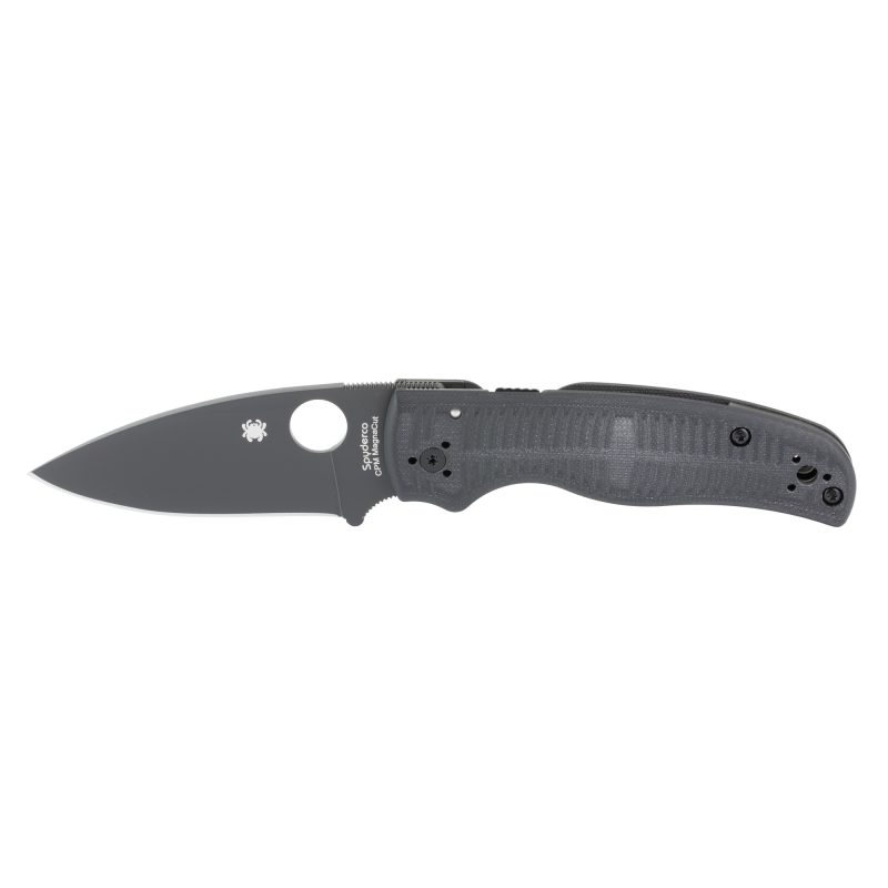Spyderco Shaman Salt folding knife with a black DLC-coated drop point MagnaCut blade and black G-10 handle, shown open on a rustic surface.