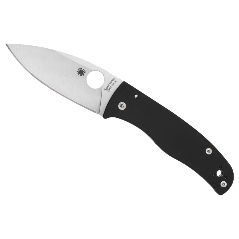 Spyderco Bodacious folding knife with black G-10 handle and satin silver CPM-S30V plain edge blade, shown open on a rustic surface.