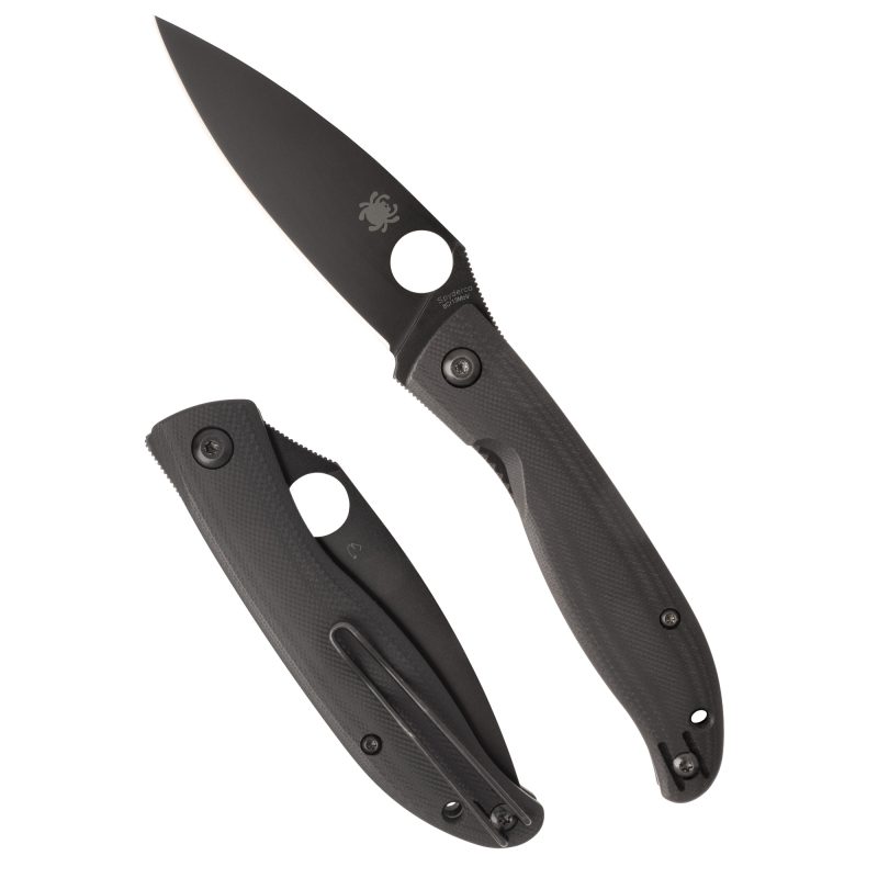 Spyderco Mantra 4 folding knife with a black G-10 handle and black oxide finished drop point blade, shown open on a rustic surface.