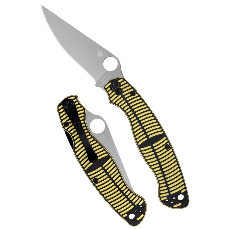 Spyderco Military 2 Salt folding knife with a silver 4-inch clip point MagnaCut blade and a black and yellow G-10 handle, shown open on a rustic surface.