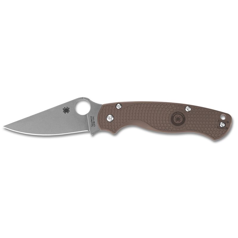 Spyderco Para Military 2 Lightweight folding knife with a brown FRN handle and a satin finish clip point blade, shown open on a rustic surface.