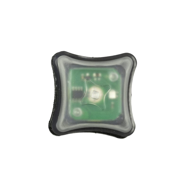 Unity Tactical Spark Light Green, a small, rectangular green LED marker light with a black Velcro backing, shown against a matte black surface.
