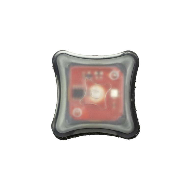 A compact, red Unity Tactical Spark marker light, shown attached to tactical gear, indicating its small size and utility for personal identification in low light conditions on a ranch.
