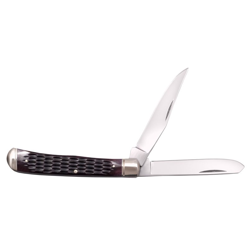 Cold Steel Trapper folding knife with yellow bone handles, two polished blades (clip point and spey), and silver bolsters, displayed on a rustic surface.